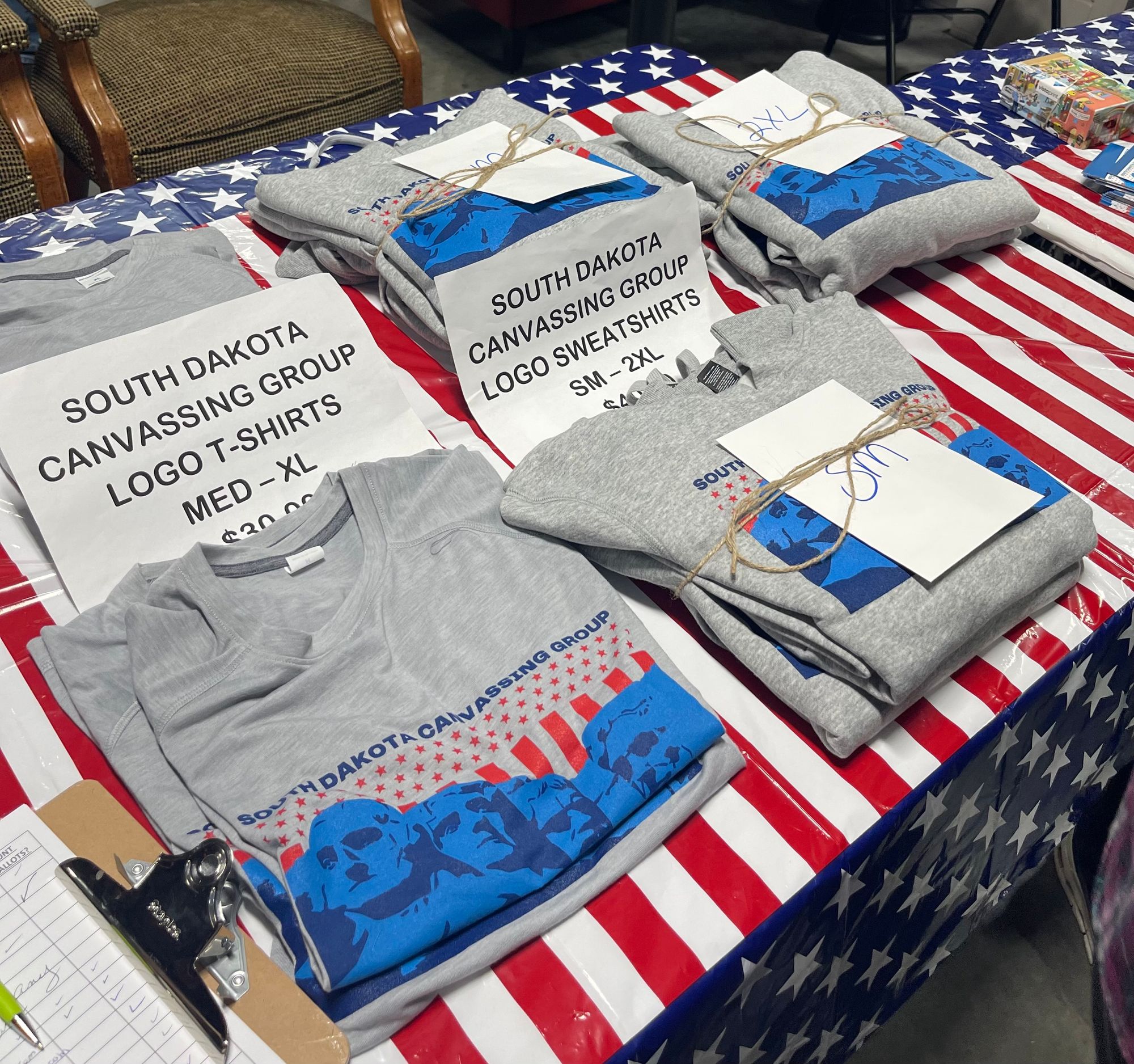 T-shirts are shown on a table at a South Dakota Canvassing  Group meeting. The T-shirts feature the image of Mount Rushmore. 
