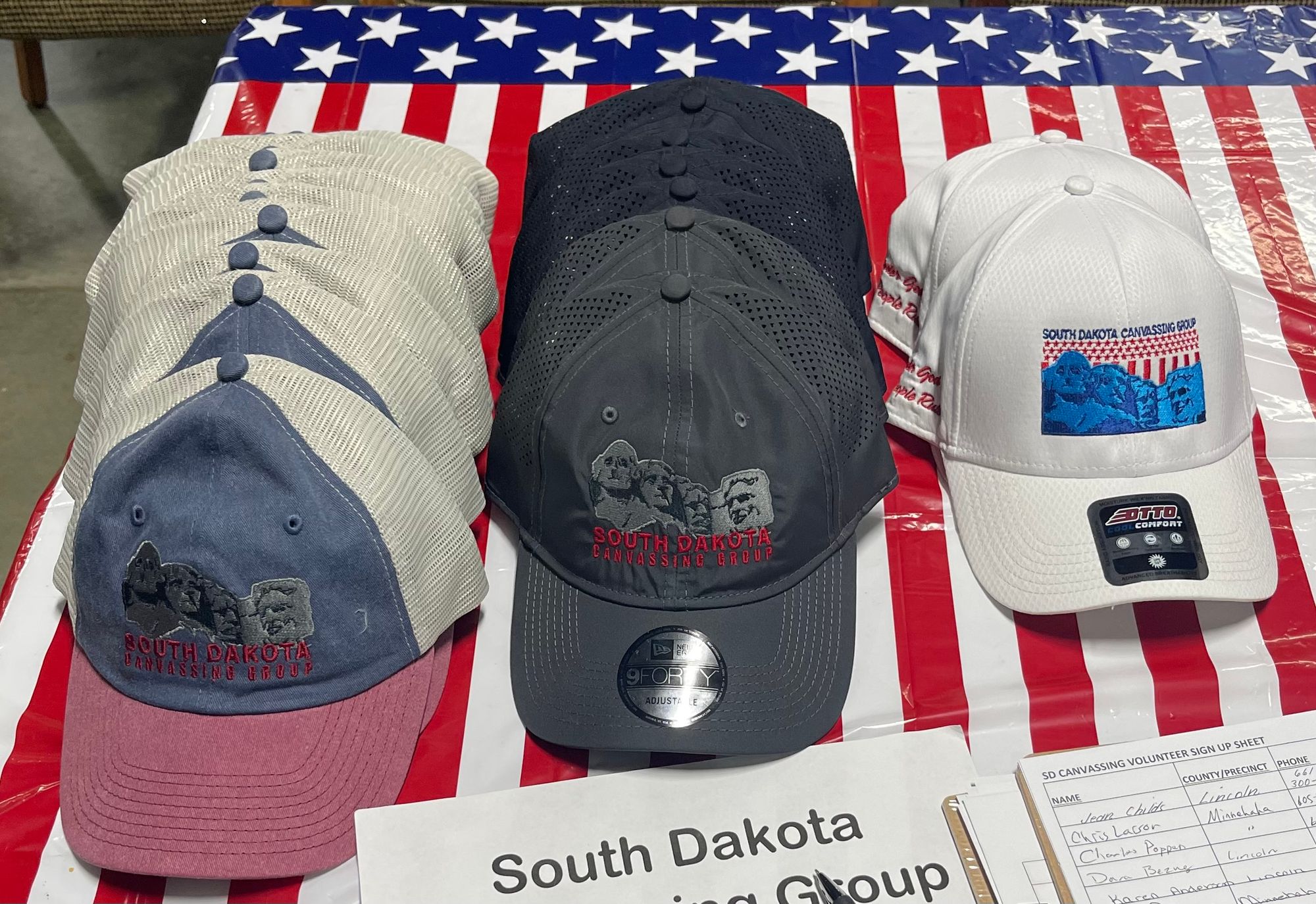 A row of caps featuring Mount Rushmore are shown on a table at the Caps for sale at a South Dakota Canvassing Group event at the Military Heritage Alliance in Sioux Falls, South Dakota.