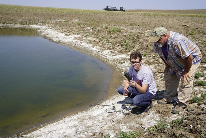 Researchers with the South Dakota School of Mines and Technology test for salinity in a stock pond