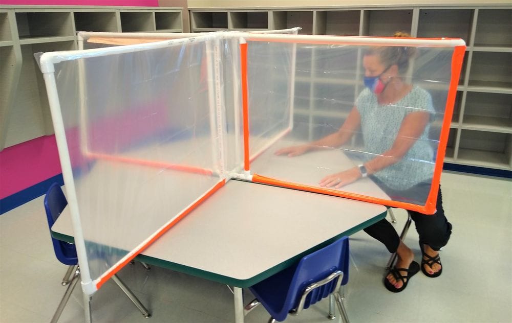 A Sioux Falls elementary school principal stands between a divider that will separate students during the Covid-19 pandemic.