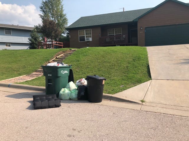 Trash is shown on a street outside of bins, violating a Hill City, South Dakota code.
