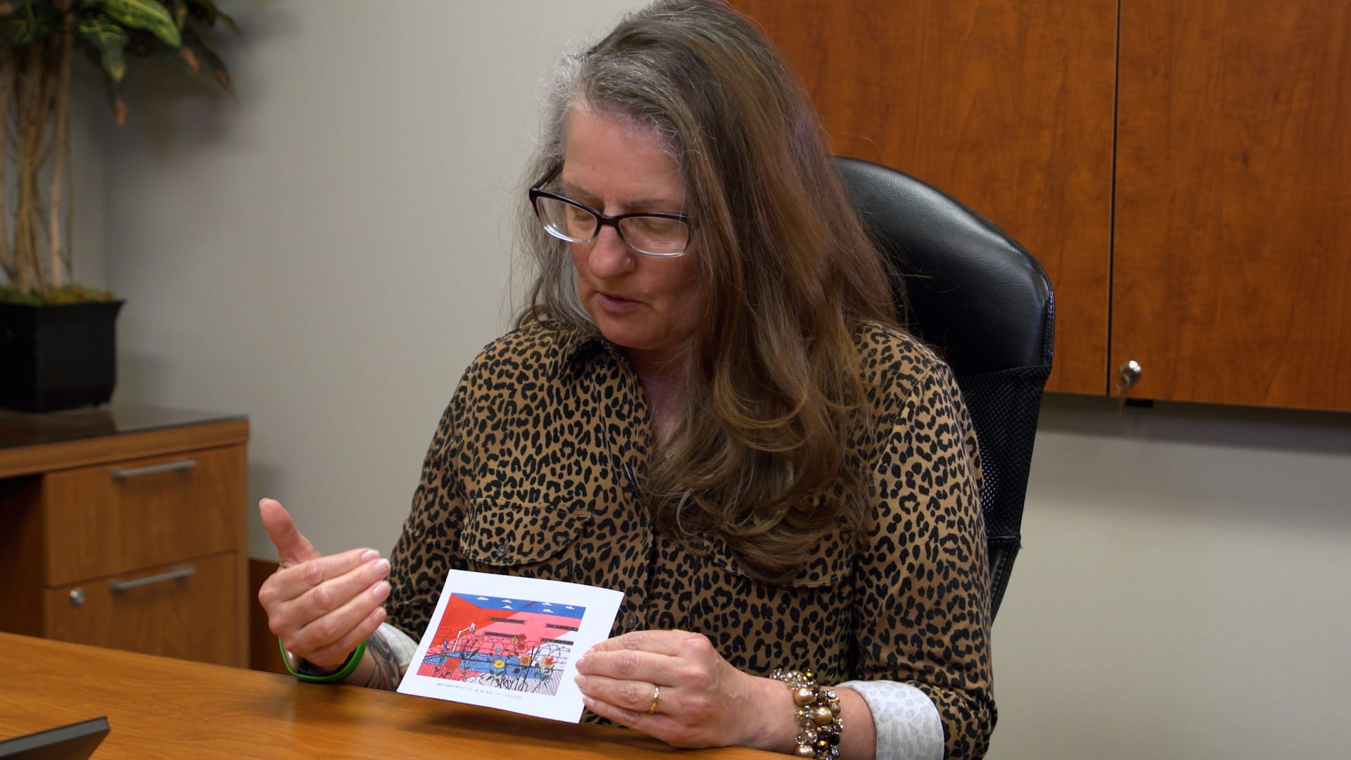 Kim Morsching, director of diversion for the Pennington County State's Attorney's Office, holds a print of a mural.