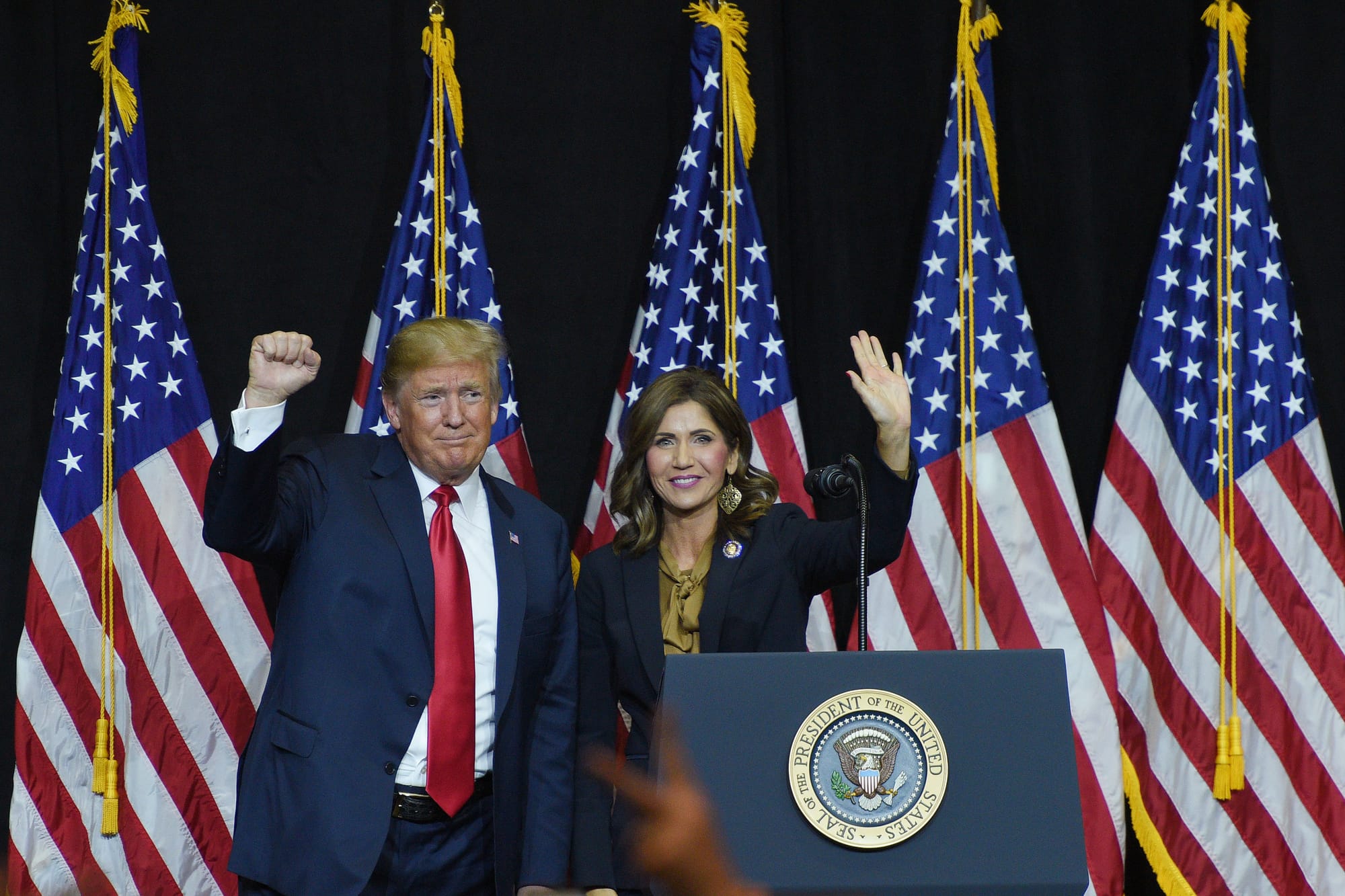 Kristi Noem waves to supporters alongside President Trump in 2018