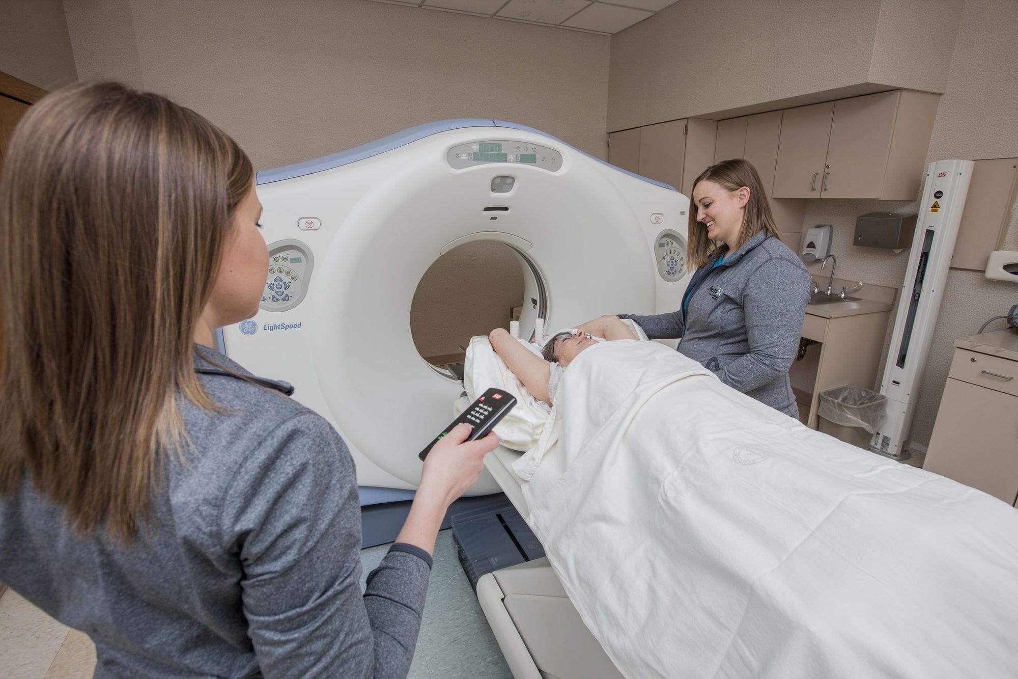 A woman undergoes an MRI treatment as two technicians look on