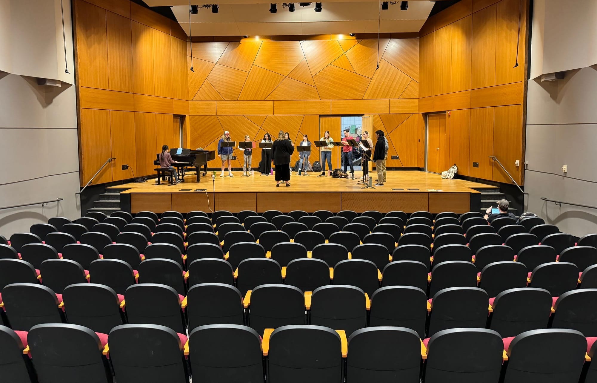 Interior of a University of South Dakota auditorium with a handful of students on the stage