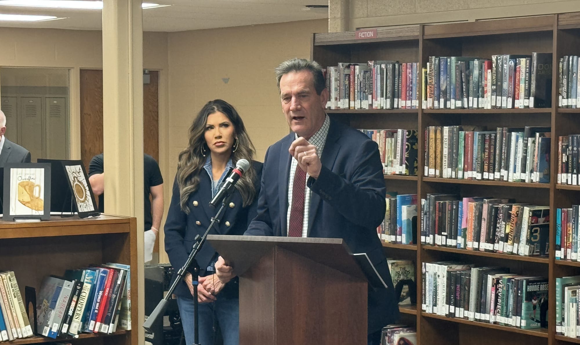 Lt. Gov. Larry Rhoden speaks to a group of supporters at a library with Gov. Kristi Noem in the background.