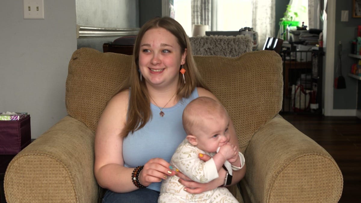 Cordelia Rieck holds a baby on a couch