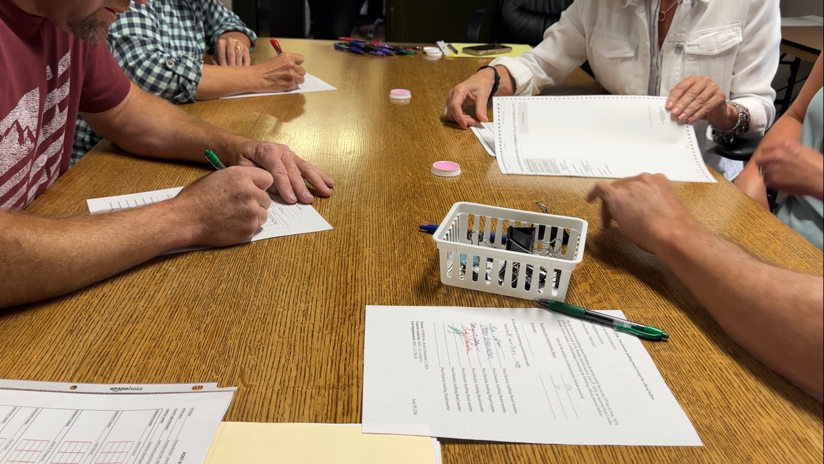 Volunteers count ballots by hand at a table