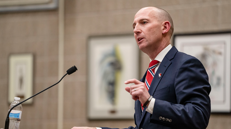 South Dakota attorney Neil Fulton stands behind a podium while speaking to a group of people