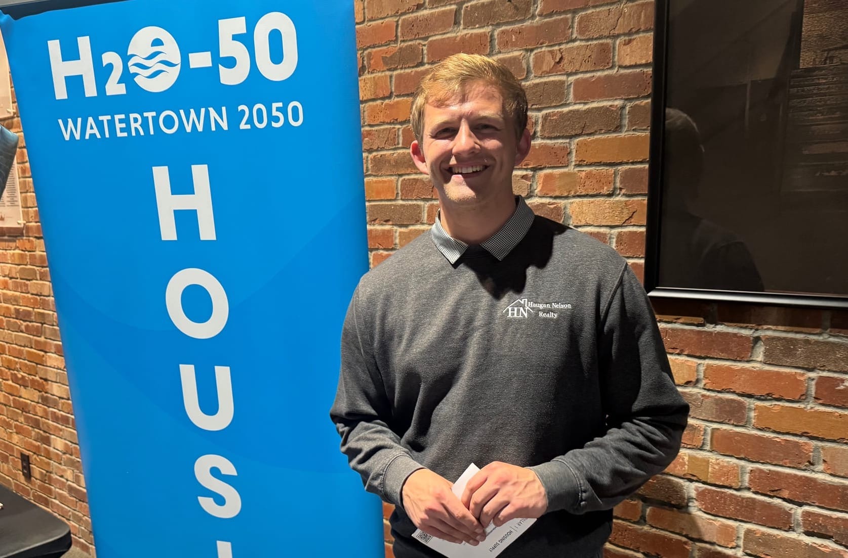 Nash Colberg, a real estate agent, poses for a photo in front of the H20-50 sign.