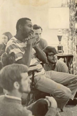 Civil rights activist Ray Robinson (center) looks forward while sitting in a room full of people