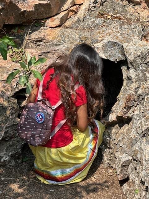 A girl kneels in front of a rock formation at Wind Cave National Park, which is a sacred site to the Lakota people. (Photo: Provided by the South Dakota Native Tourism Alliance)