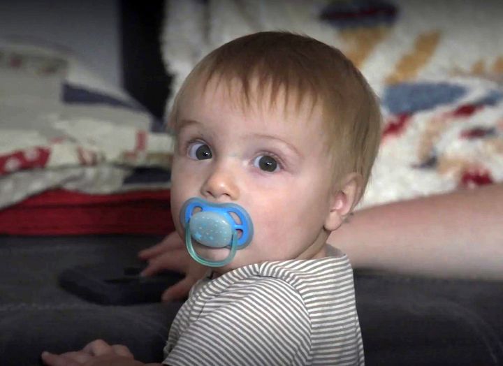 A child with a pacifier in his mouth looks at the camera 