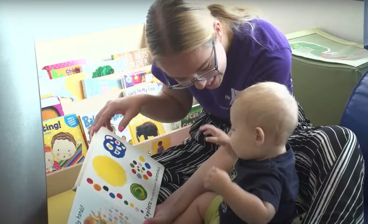 A child care provider reads a book to a baby.