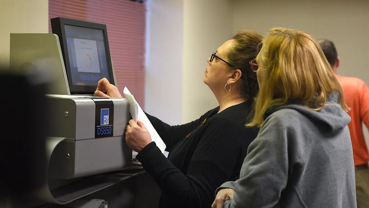 Poll workers put ballots into a tabulation machine in Sioux Falls, South Dakota