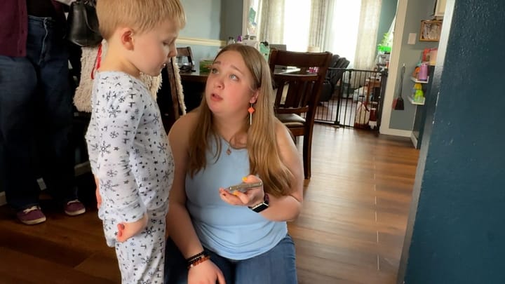 Woman gets down on a child's level and talks to him in a house.
