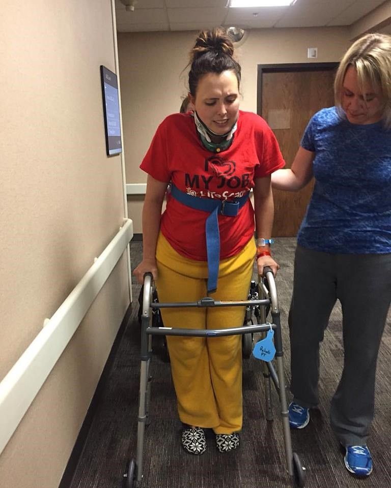 woman with pained face using walker during rehab